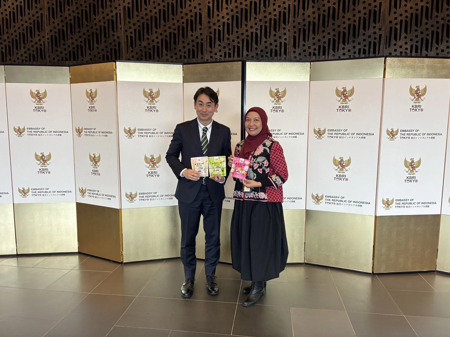 インドネシア共和国大使館で商務部長と面会し、テンペチップスを手にする様子